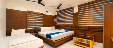 A modern hotel room with a large bed, a smaller bed, and a bench. There are ceiling fans and wooden paneling on the walls.