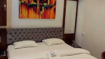 Habitación de hotel con una cama grande, un ventilador de techo, un cuadro en la pared y una alfombra con motivos rojos y negros.
