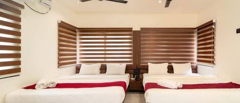 A hotel room with two beds, wooden headboards, ceiling fans, and a minibar.