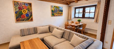 A cozy living room with a wooden ceiling, a sofa, a coffee table, and two paintings on the wall.