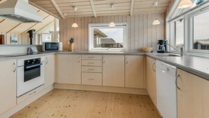 Una cocina moderna con vigas de madera en el techo, horno empotrado, microondas y ventana con vistas.