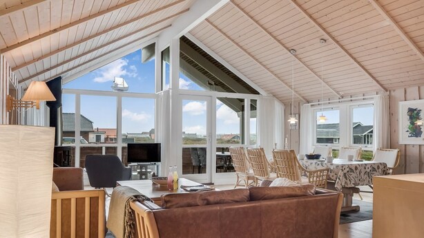 Un espacio habitable amplio con techos altos, ventanas grandes y vistas al mar.
