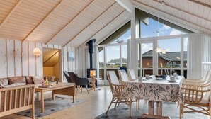 Una habitación amplia con techo alto, paredes de madera y ventanas grandes que ofrecen vistas al exterior.