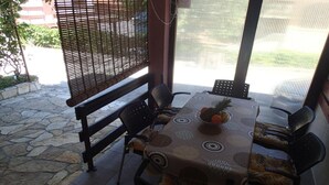 Eine Terrasse im Freien mit einem für vier Personen gedeckten Tisch, umgeben von Stühlen.
