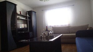 Ein Wohnzimmer mit einem dunklen Holzschrank, einer Couch und einem Couchtisch mit Weingläsern und einer Weinflasche.