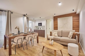 Uma sala de estar moderna com área de jantar, sofá e cozinha ao fundo.