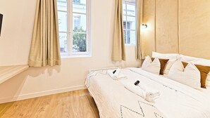 Ein Hotelzimmer mit Bett, Vorhängen, einem Fenster und einem Kopfteil.