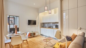 A modern living room with a sofa, coffee table, and dining area with chairs and a table set for two. - Superb Apartement Center of Paris Le Marais (Paris)