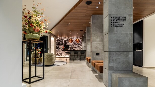 A modern lobby with a reception desk, seating area, and a wall with directional signs. - comfortable apartment with panoramic views (Den Haag)