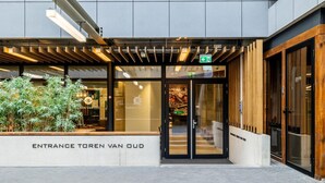 The entrance to a building with a modern design, featuring a glass door, wooden accents, and a sign indicating an entrance. - comfortable apartment with panoramic views (Den Haag)