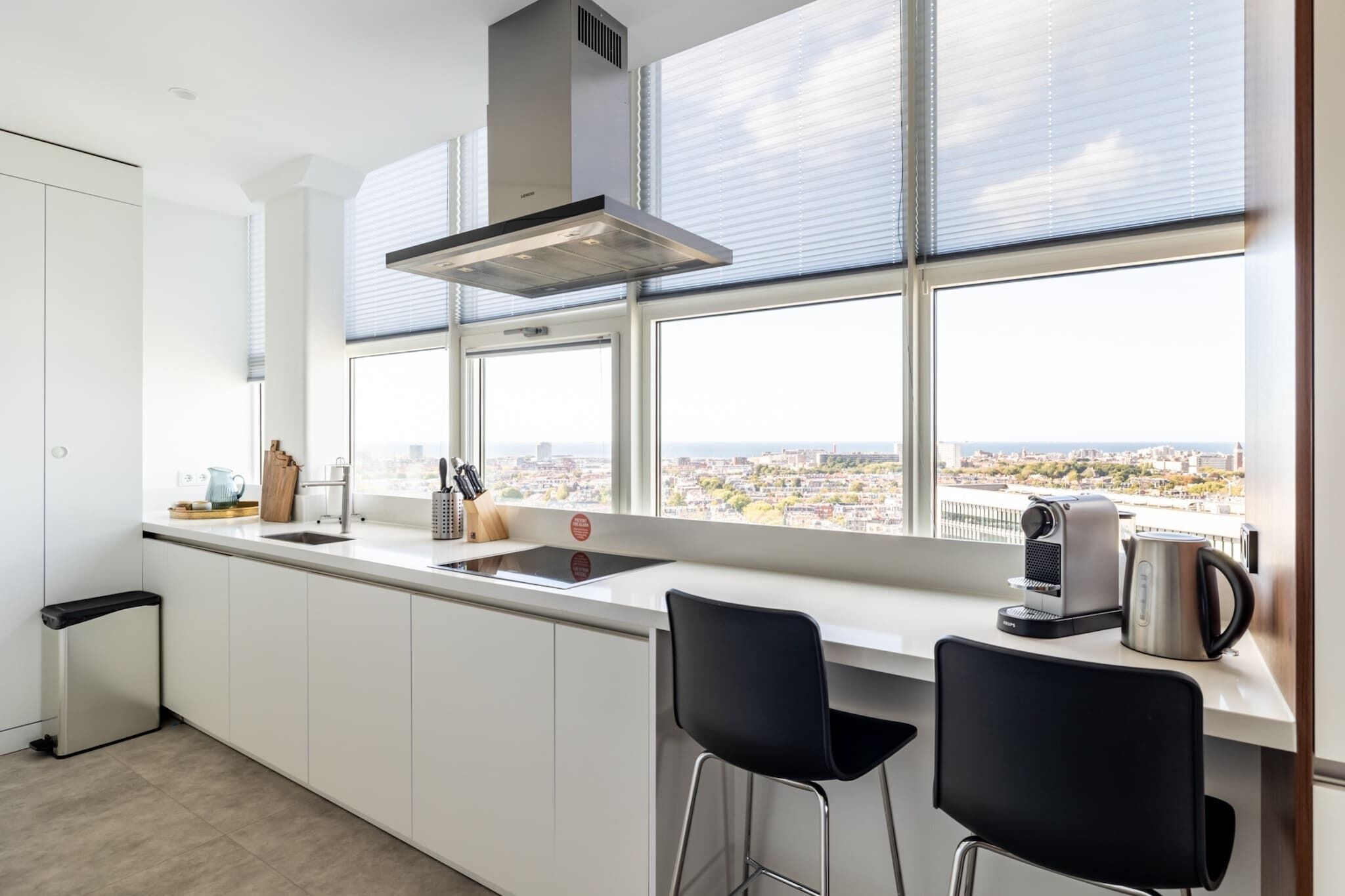 Een moderne keuken met een groot raam, een ingebouwde kookplaat en een koffiezetapparaat.