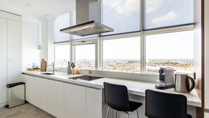 A modern kitchen with a large window, a built-in stove, and a coffee maker. - comfortable apartment with panoramic views (Den Haag)
