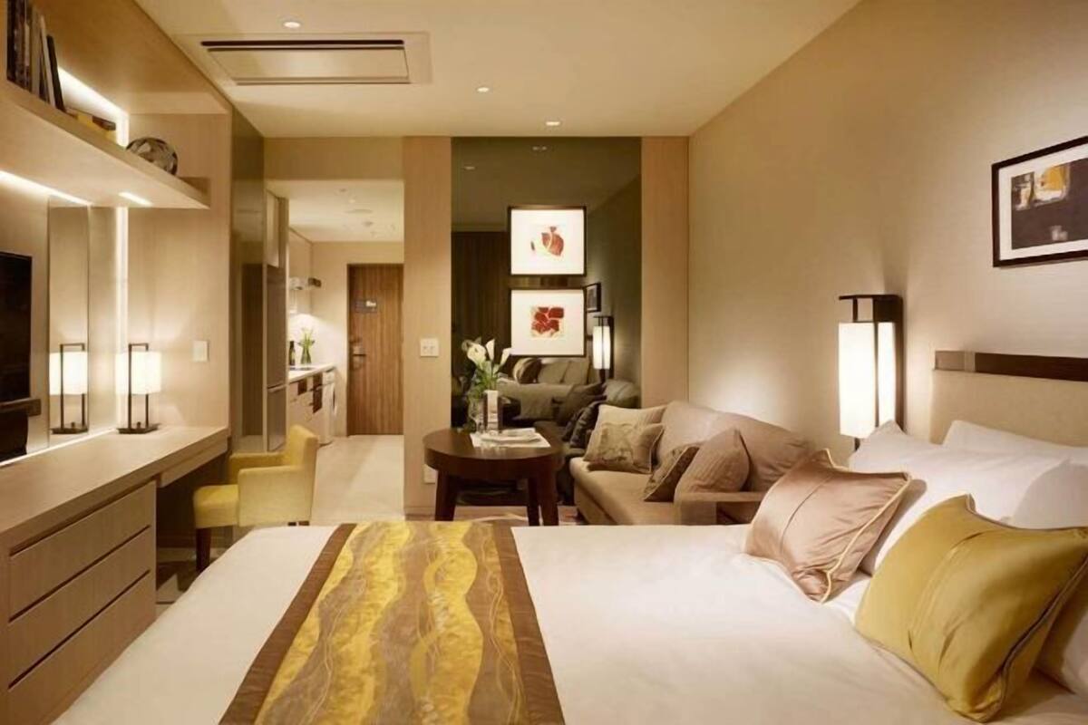 Une chambre d’hôtel comprenant un lit, un bureau, une chaise, un canapé et un téléviseur.