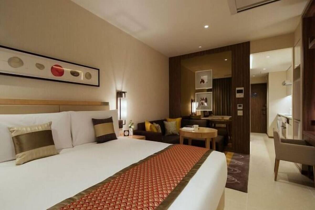 Une chambre d’hôtel avec un grand lit, un canapé, une petite table et un bureau.