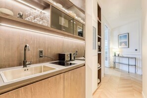 A modern kitchen with a built-in oven, microwave, and sink. There is a wooden countertop and a hallway leading to a dining area. - Wonderful AC Apartment Terrace Madeleine Opera (Paris)
