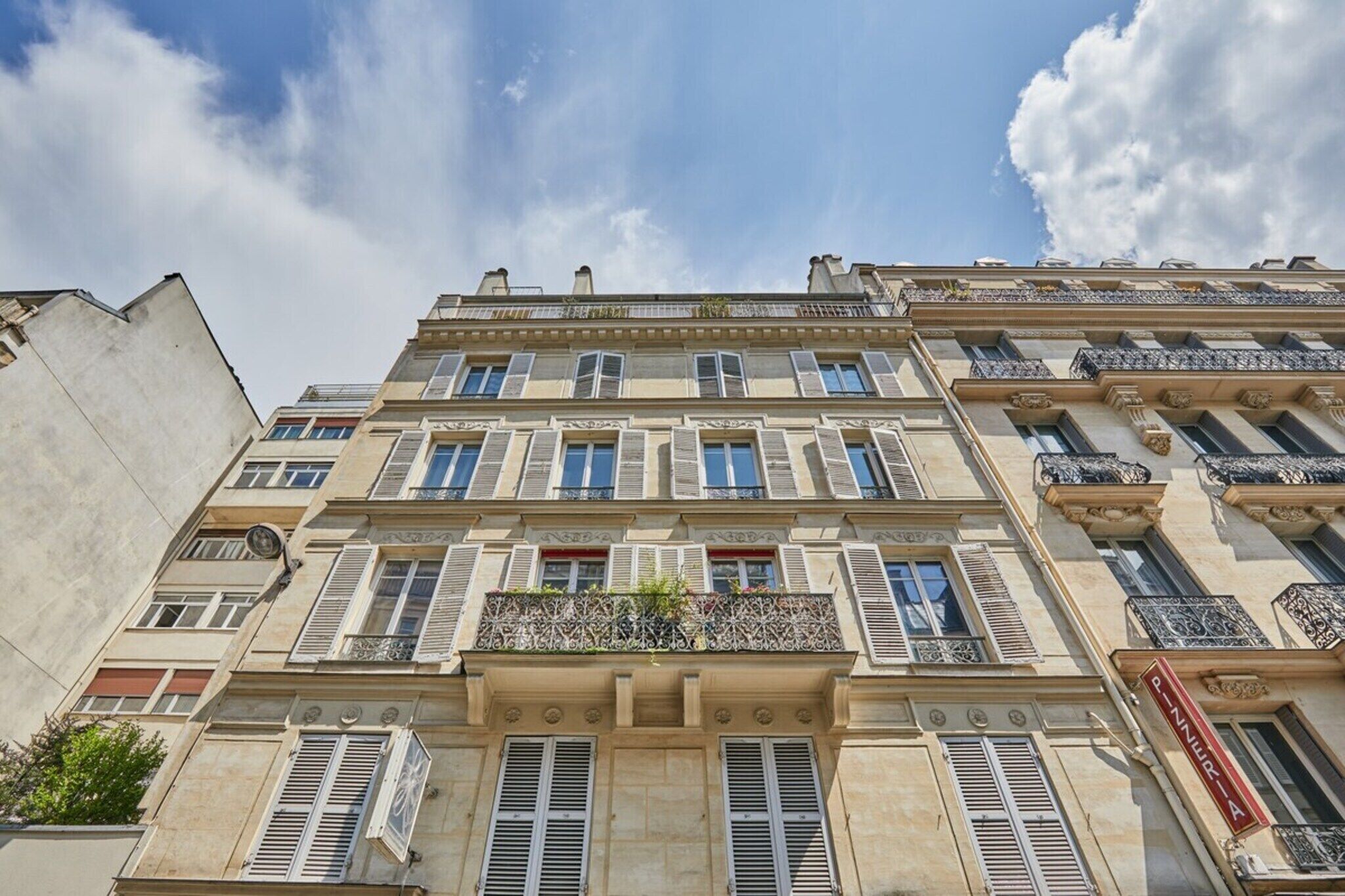 A multi-story building with classic architectural features, including symmetrical windows, shutters, and decorative balconies.