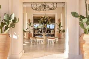 A grand entrance with a chandelier, a central floral arrangement, and potted plants. - Grecotel Eva Palace (Limni)