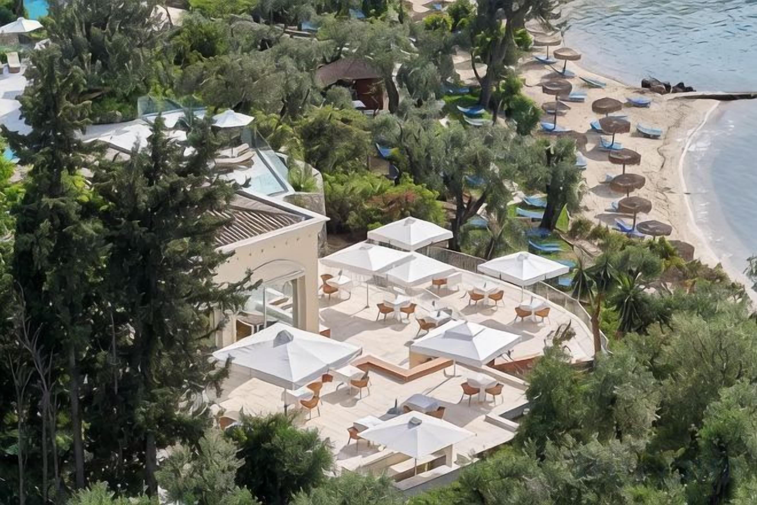 A resort with outdoor seating areas, a pool, and a beach.