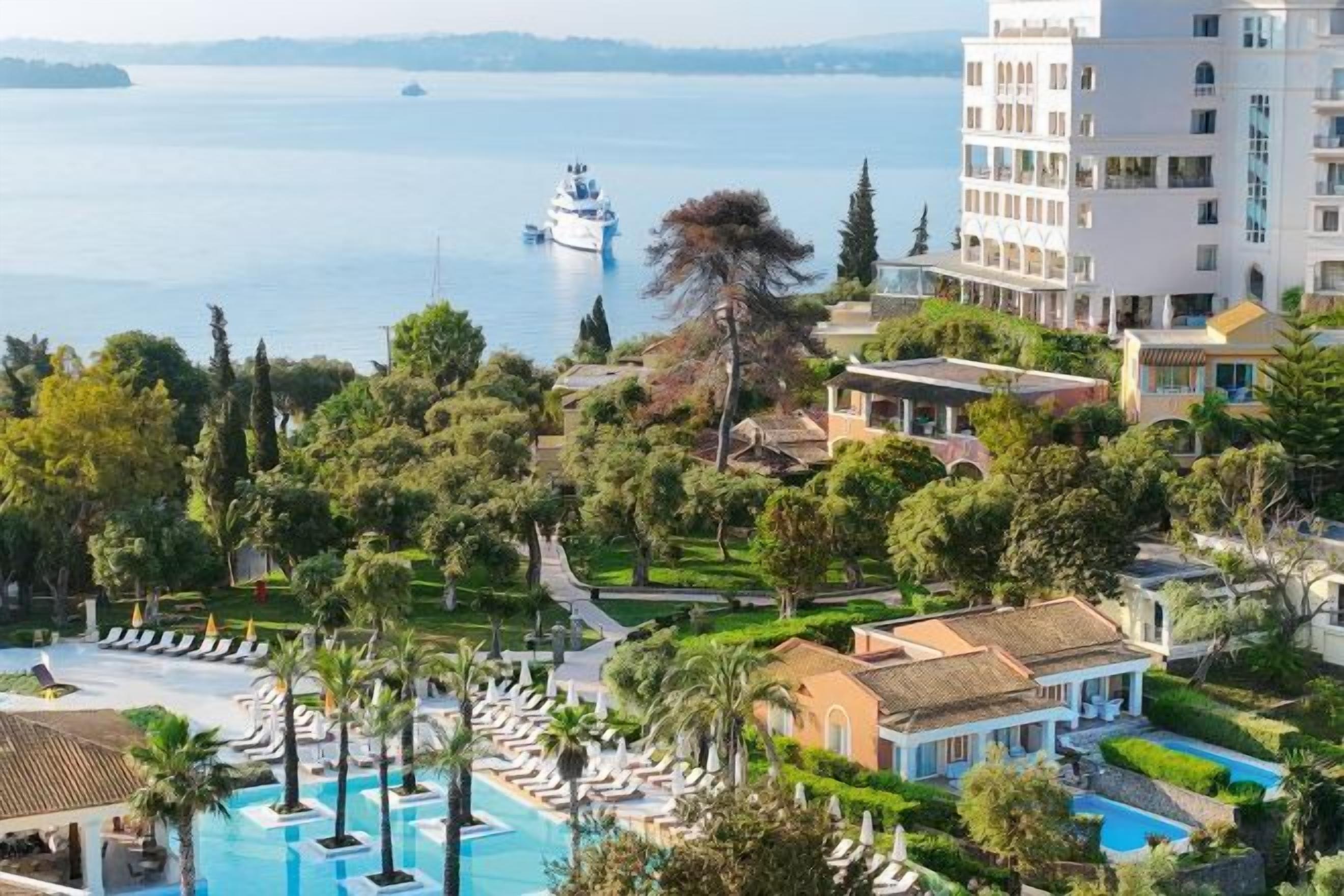 Un resort con piscina, un barco en el agua y vista al mar.