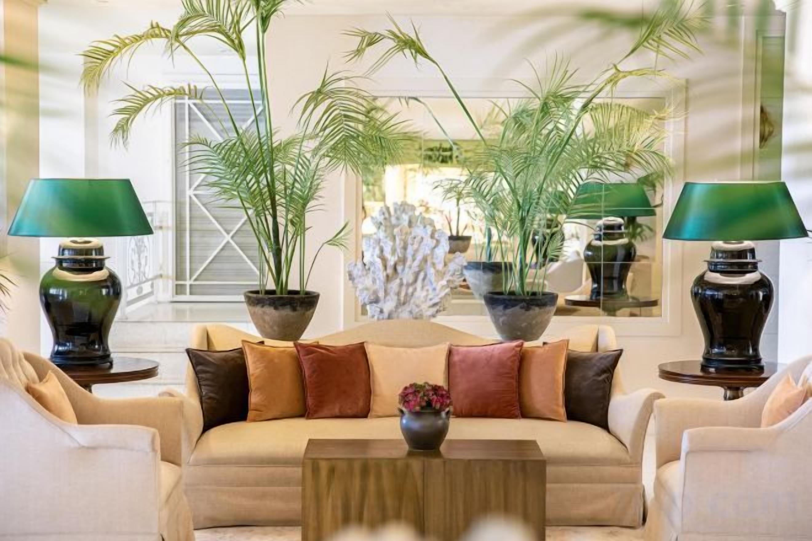 A lobby with a sofa, two lamps, and potted plants.