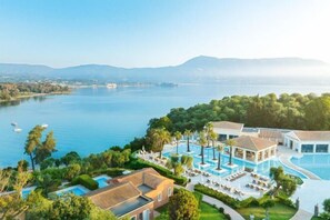 A resort with multiple swimming pools, a large lake, and surrounding greenery. - Grecotel Eva Palace (Limni)