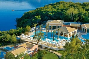 Un resort con varias piscinas, un pabellón y vista al mar.