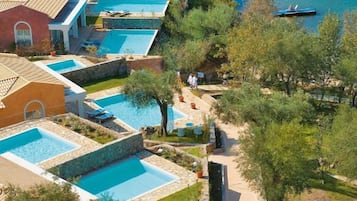A resort with multiple swimming pools, a beach area, and a boat on the water.