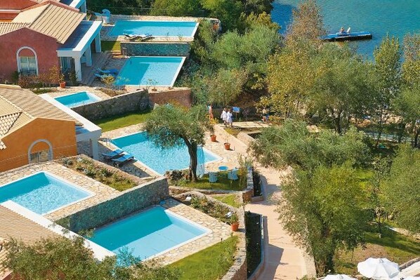 A resort with multiple swimming pools, a beach area, and a boat on the water.