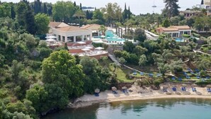 A coastal resort with a pool area, a beach, and lush greenery. - Grecotel Eva Palace (Limni)
