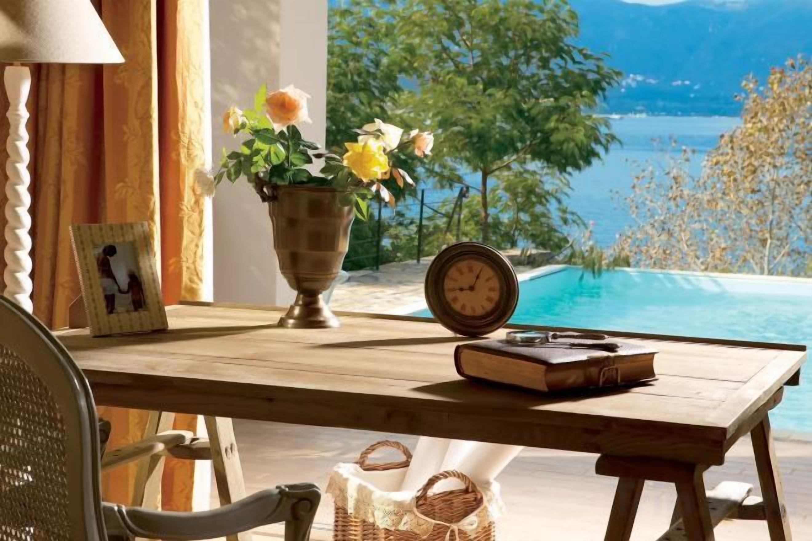 Una mesa de madera con un florero, un reloj y un libro.