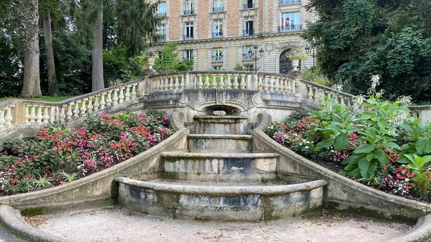A stone staircase leading up to a building with multiple windows and balconies, surrounded by lush greenery and flowering plants. - Charming appartement with roof terrace in Vittel (Vittel)