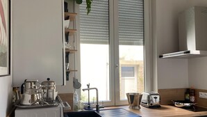 Una cocina moderna con horno integrado, cafetera, hervidor y tostadora.