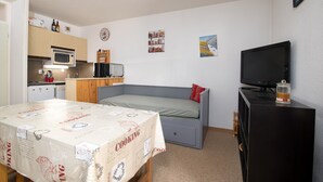 A compact room with a kitchenette, a bed, a television, and a small table.