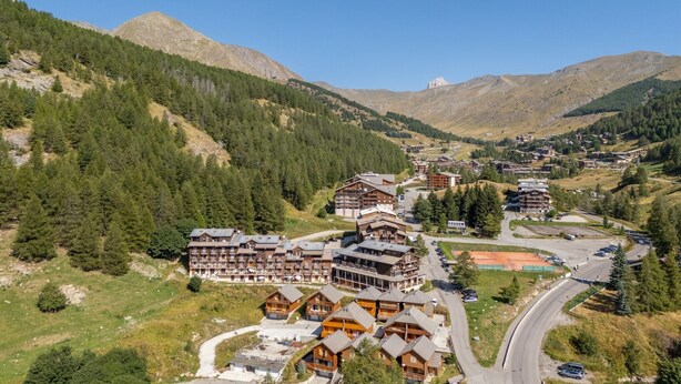 A mountainous resort with multiple wooden buildings, winding roads, and dense forested areas.