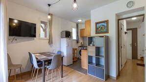 Un espace de vie compact comprenant un coin repas, une kitchenette et un petit espace de rangement.