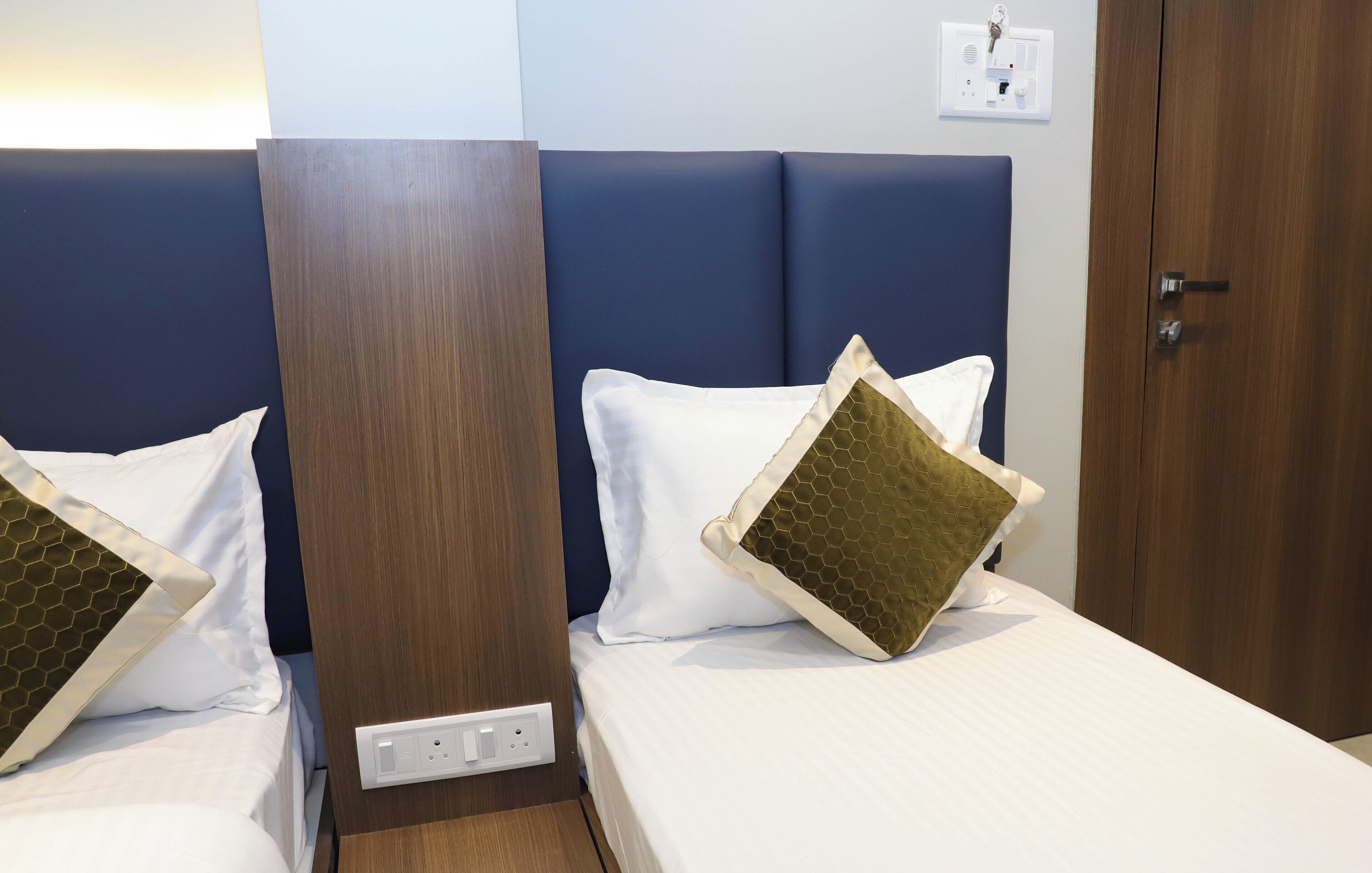 A hotel room with two beds, each with white bedding and honeycomb-patterned pillows.