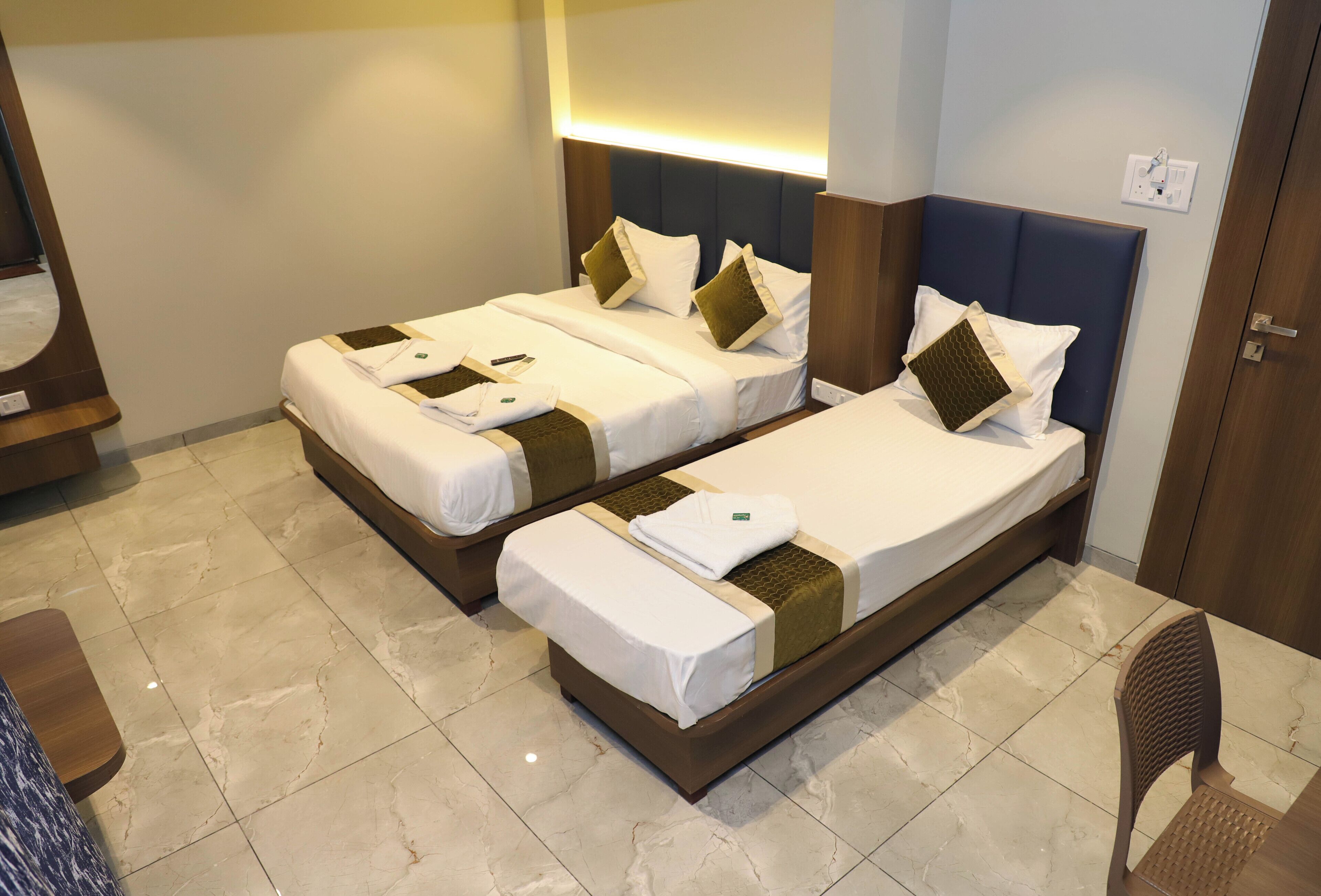 A hotel room with two beds, a wooden headboard, a small table, and a chair.