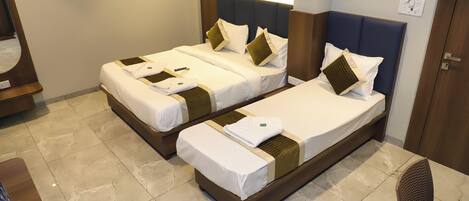 A hotel room with two beds, a wooden headboard, a small table, and a chair.