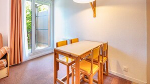 Ein Essbereich mit einem Holztisch und gelben Stühlen, einer Schiebeglastür zum Außenbereich und einer Wandlampe.