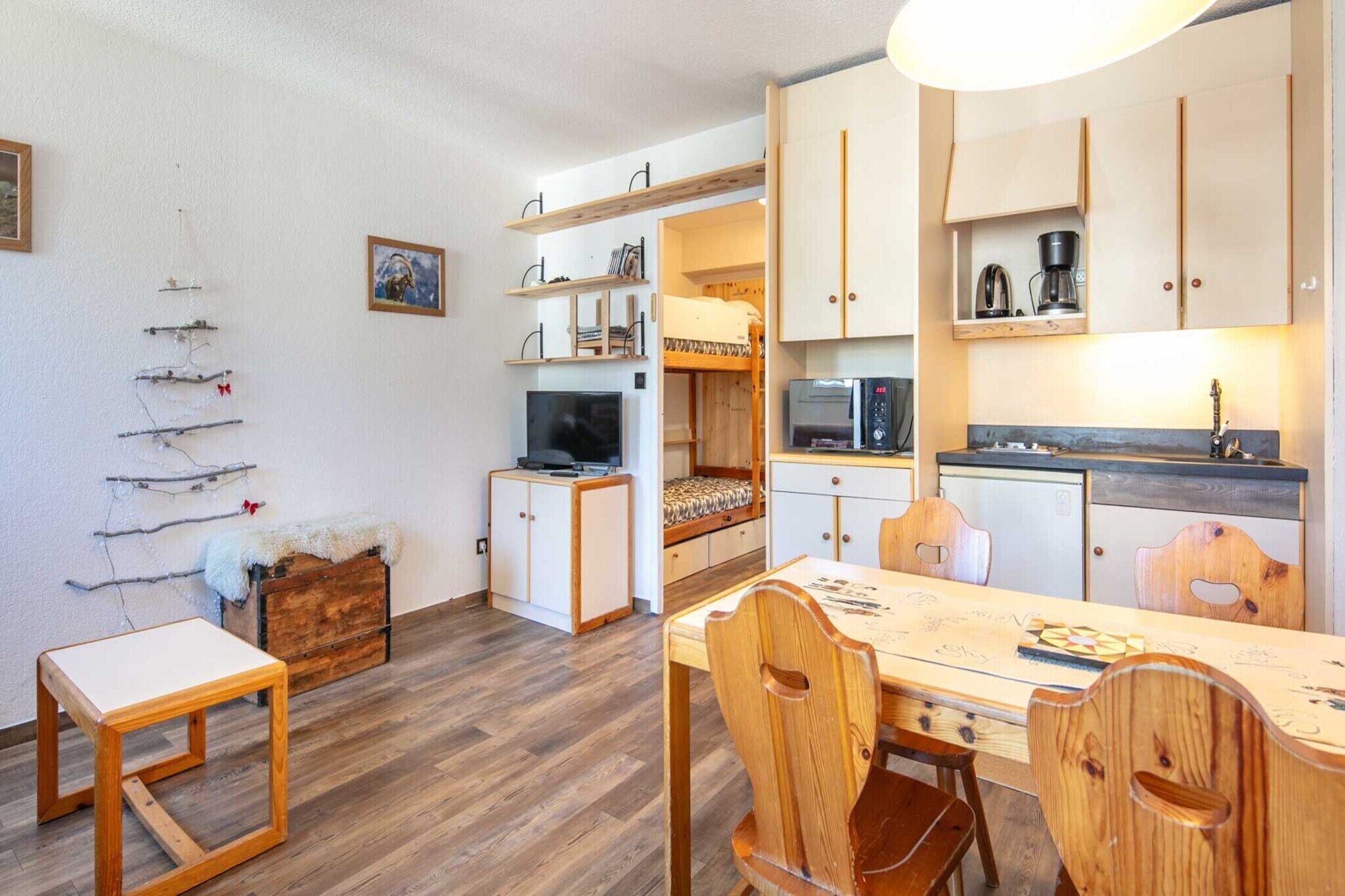 Espacio habitable compacto con comedor, kitchenette y cama con vistas.