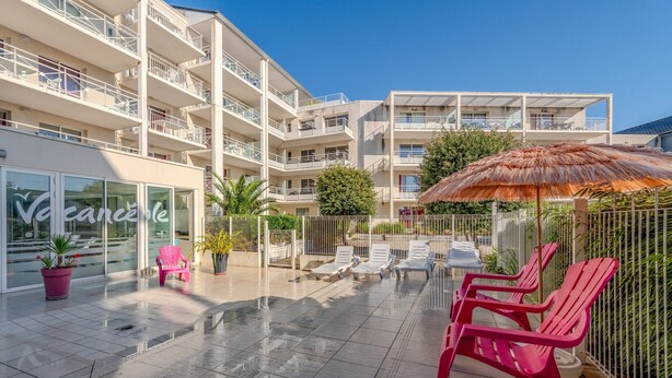 Un patio moderno de hotel con piscina, tumbonas y un restaurante llamado "Vacances".