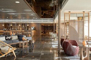 A modern hotel lobby with a seating area, a bar, and a staircase. - Wyndham Grand Crete Mirabello Bay (Agios Nikolaos)