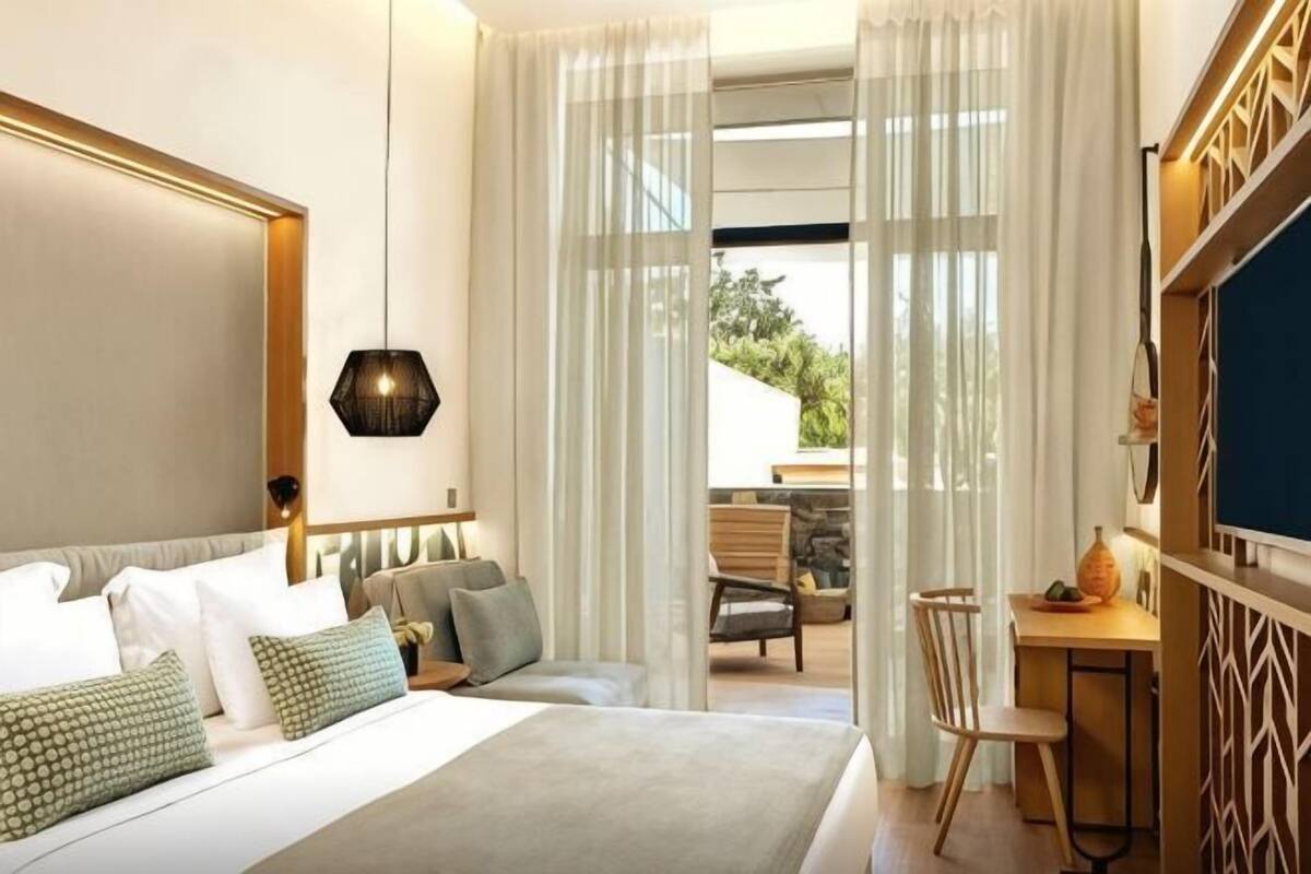 A bedroom with a bed, a desk, and a view of the outdoors.