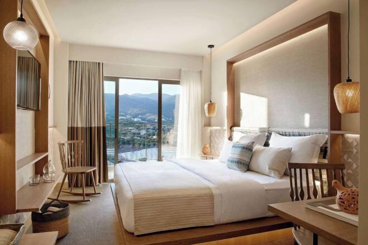 A hotel room with a large bed, a view of the city, and a balcony.