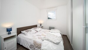 A bedroom with a bed, bedside tables, a nightstand, a window, and a ceiling light. - Family-friendly apartment with terrace (Allos)