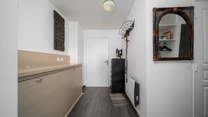 A narrow hallway with a wooden cabinet, a radiator, a mirror, and a door leading to a room. - Family-friendly apartment with terrace (Allos)