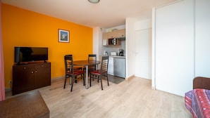 Un espacio habitable compacto con comedor, kitchenette y televisor.