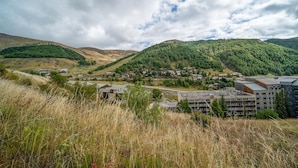 Un pueblo ubicado en un valle, con edificios residenciales y comerciales, rodeado de colinas boscosas.