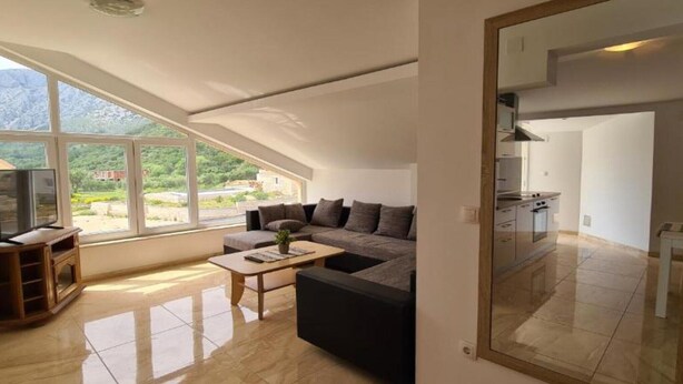 A modern living room with a large window, a sofa, a coffee table, and a TV.