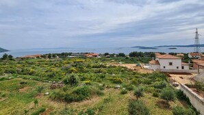 A coastal landscape with houses, greenery, and a power line tower.